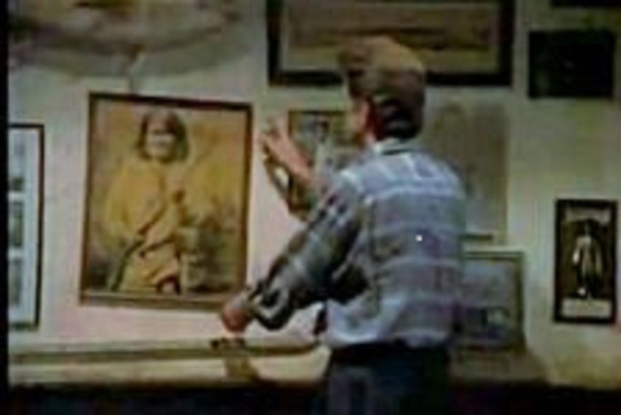 Sam Malone adjusts a photo of Geronimo. 